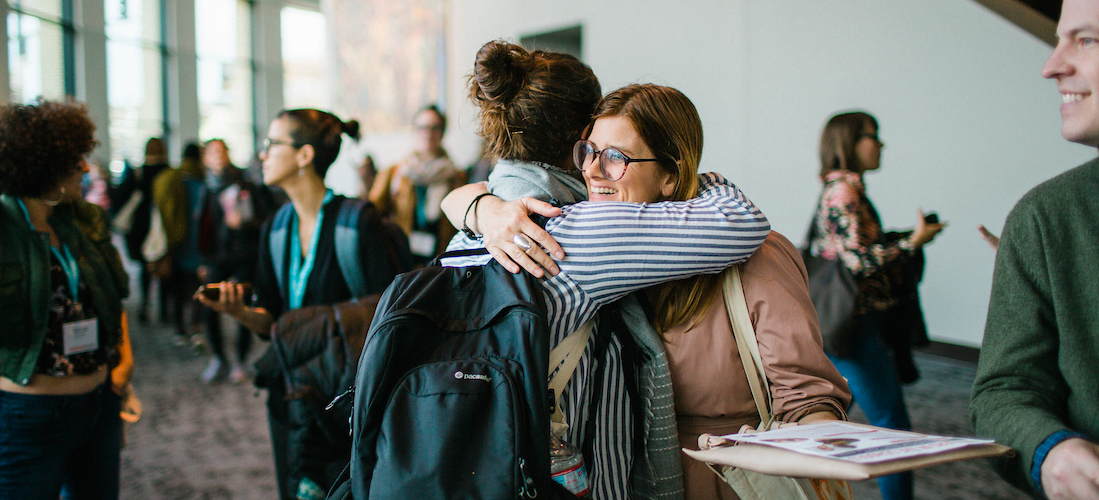 Image of two people hugging at #AWP19 in Portland, Oregon.