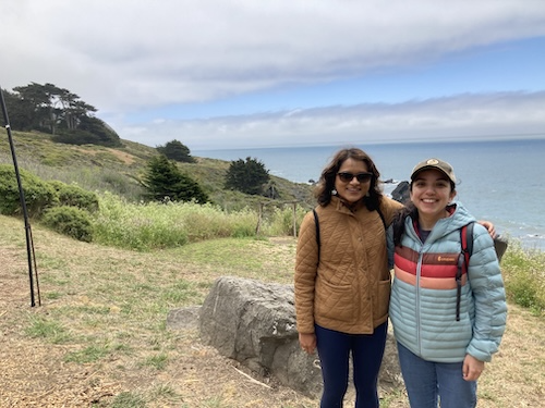 Two people posing with arms around each other in front of ocean