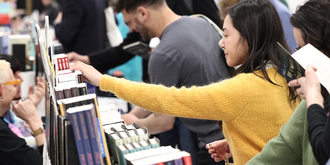 Image of bookfair attendee reaching for a book.