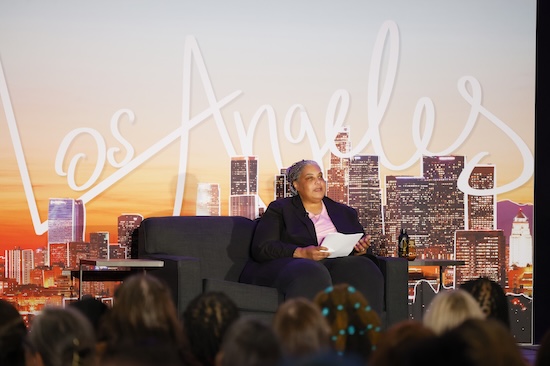 Roxane Gay delivering keynote address in front of a backdrop with the LA skyline