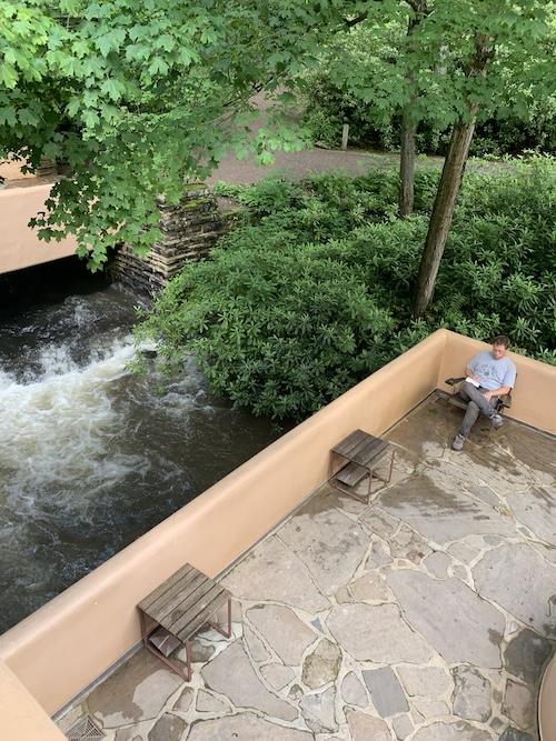 Aerial view of person writing on Fallingwater balcony overlooking waterfall
